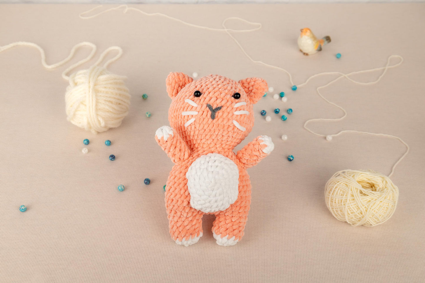 a crocheted cat next to a ball of yarn
