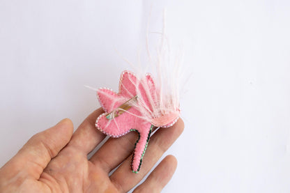 a hand holding a pink flower with white feathers