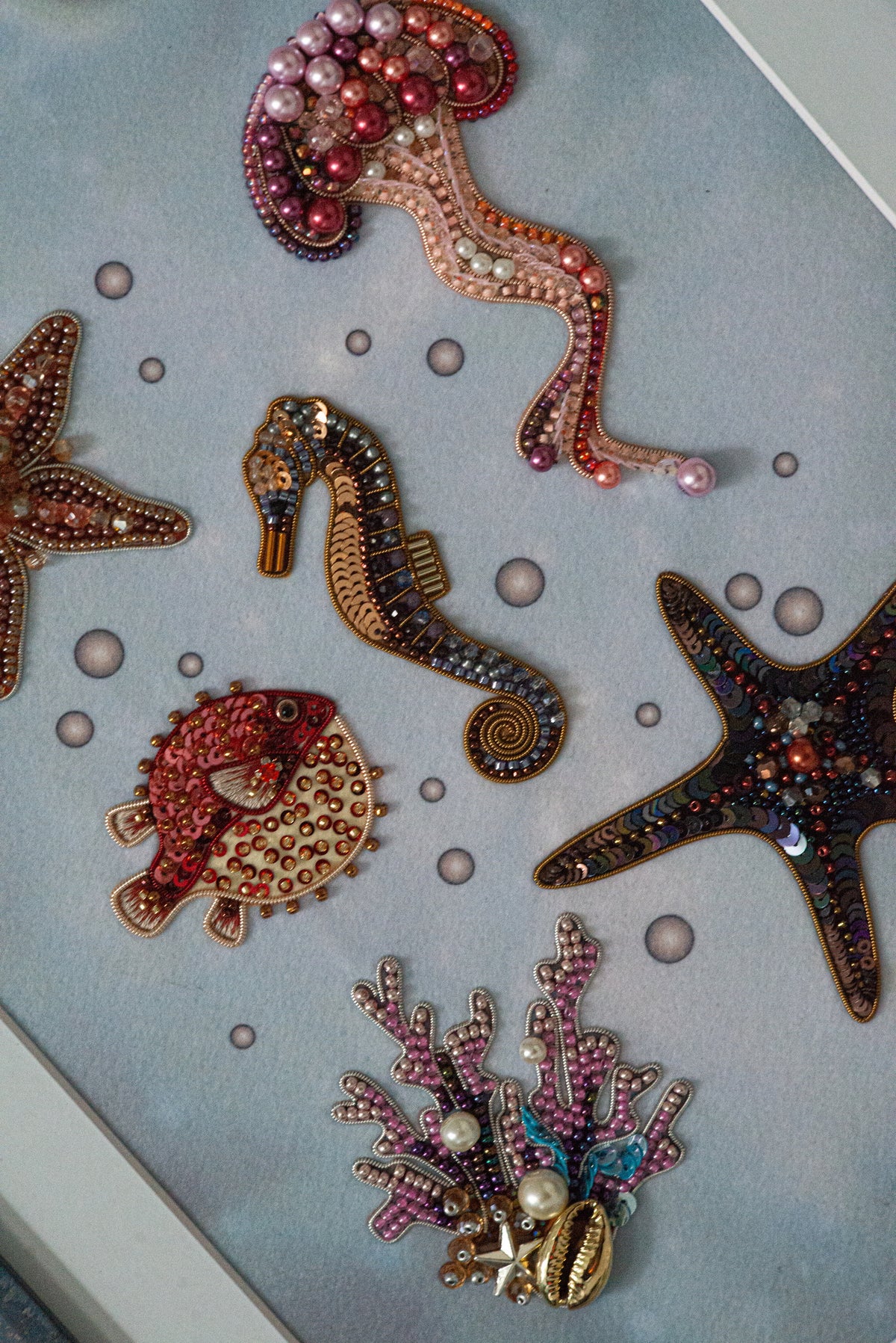 a collection of colorful, intricately designed sea-themed ornaments, including a jellyfish, a seahorse, a starfish, and a coral. The ornaments are arranged in a visually appealing manner, showcasing the craftsmanship and creativity involved in their design.