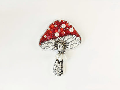 a red and white brooch with pearls on it