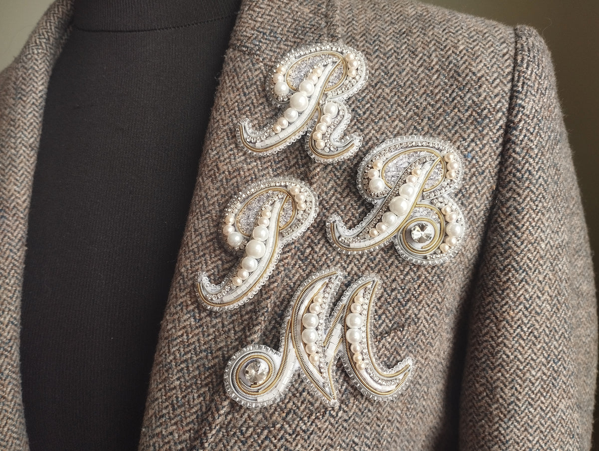 a close-up of a jacket with a decorative embroidered letter on the front.