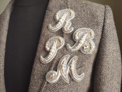 a close-up of a jacket with a decorative embroidered letter on the front.
