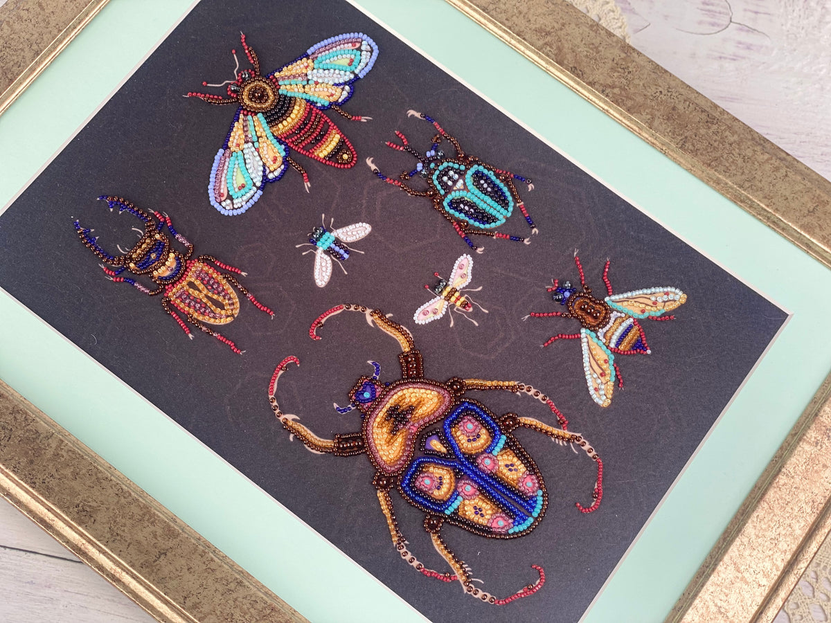 a framed artwork depicting a variety of colorful and intricate insects, including a large dragonfly, a group of bees, and several other types of bugs.