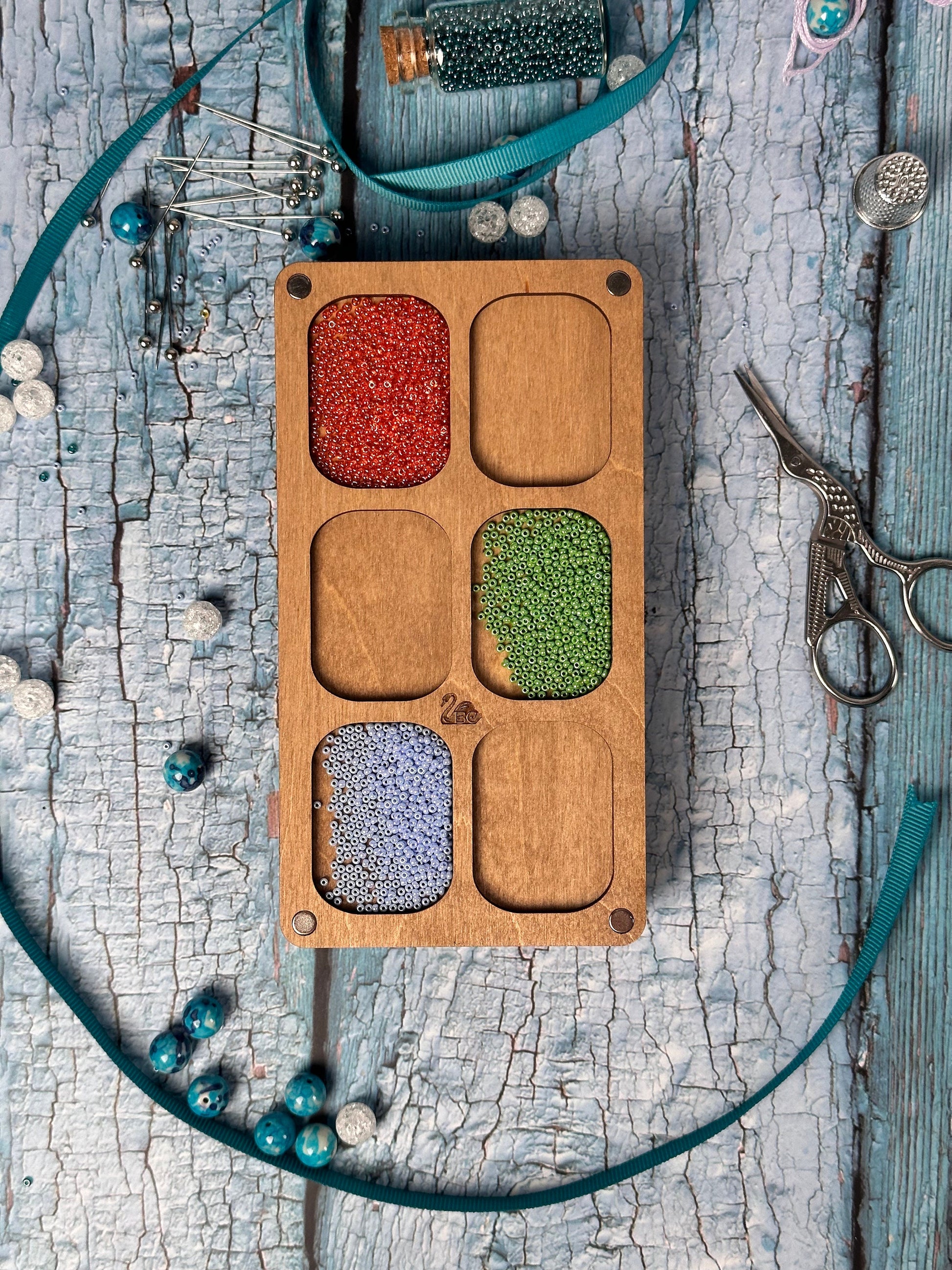 a wooden tray with beads and a pair of scissors