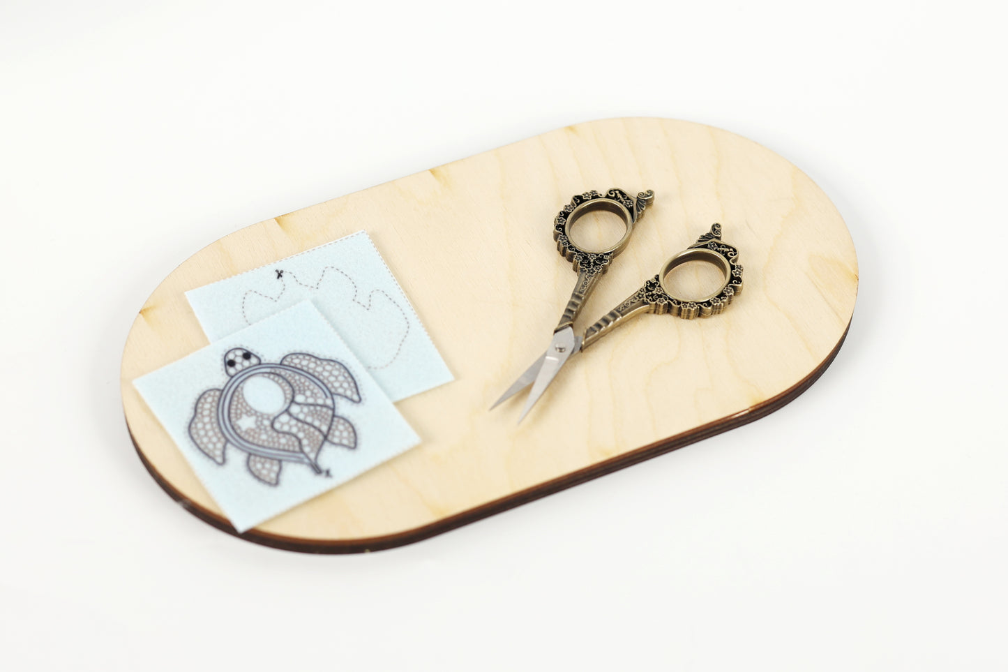 a pair of ornate scissors, a piece of paper with a drawing of a turtle, and a small piece of paper with a drawing of a bird.