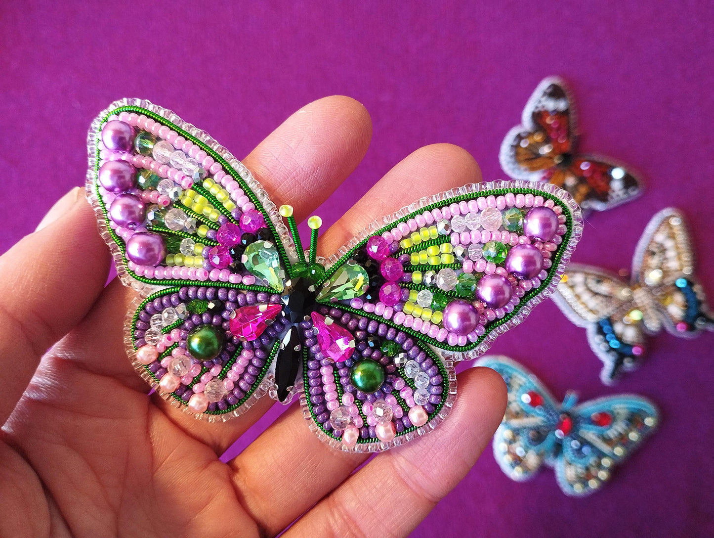 a hand is holding a small butterfly brooch