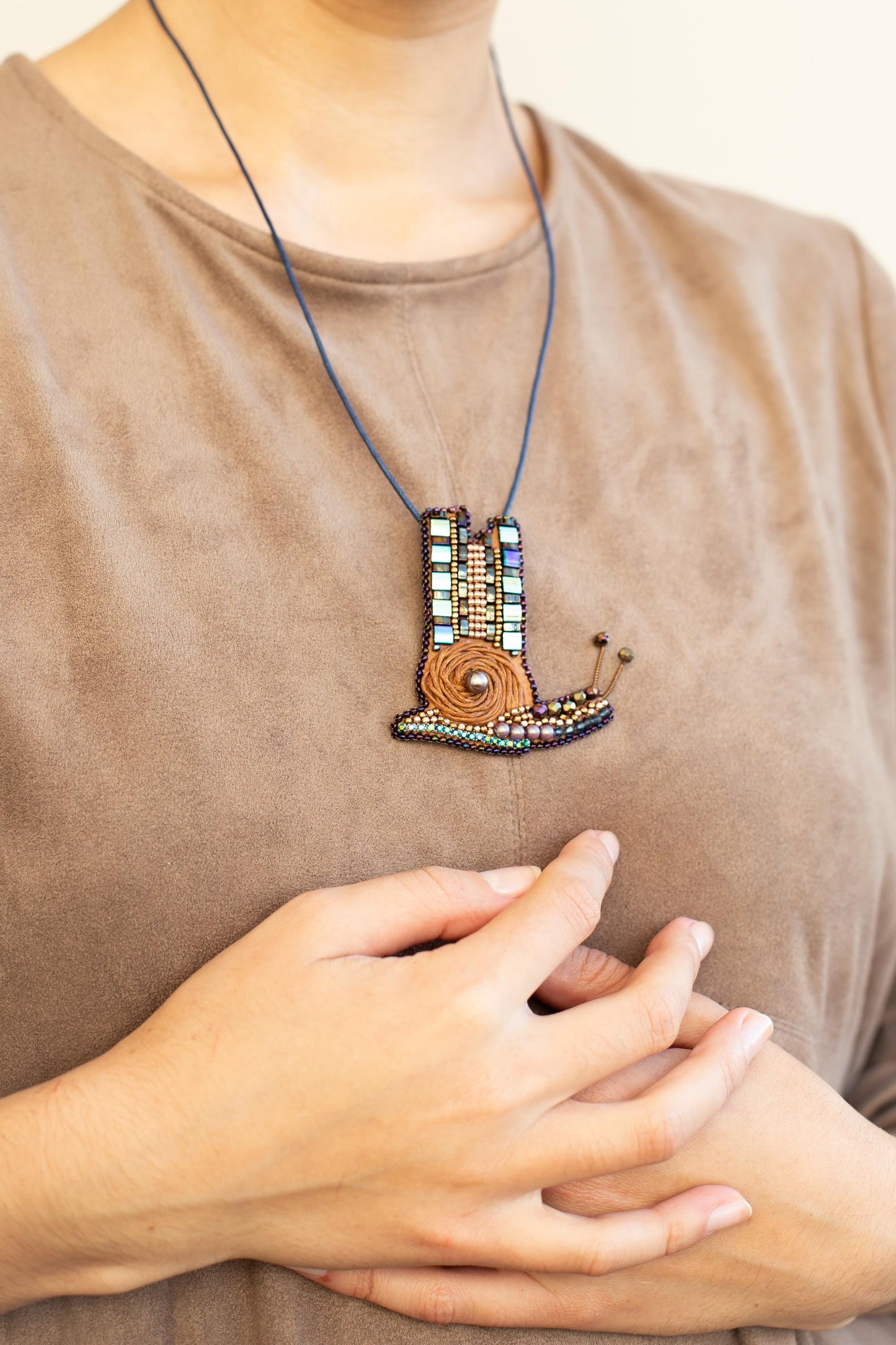 a woman wearing a brown shirt and a necklace with a picture of a hand holding