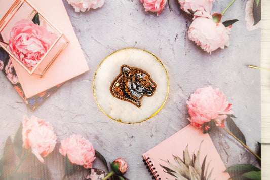 a tiger brooch sitting on top of a white plate