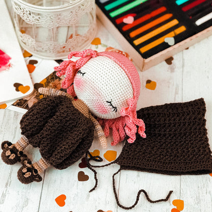 a crocheted doll laying on a table next to a box of crayo