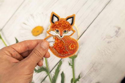 a hand holding a piece of beaded fabric with a fox on it