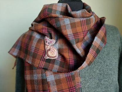 A plaid scarf with a decorative cat embroidered on it, displayed on a mannequin.