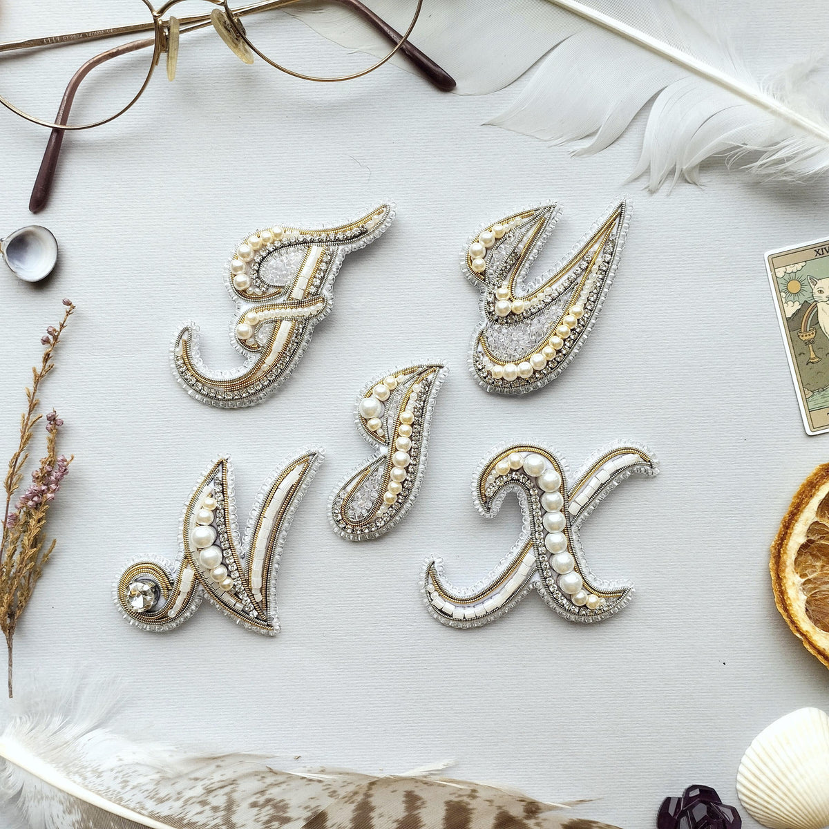 a collection of decorative elements arranged on a white background, including a pair of glasses, feathers, and pearls.