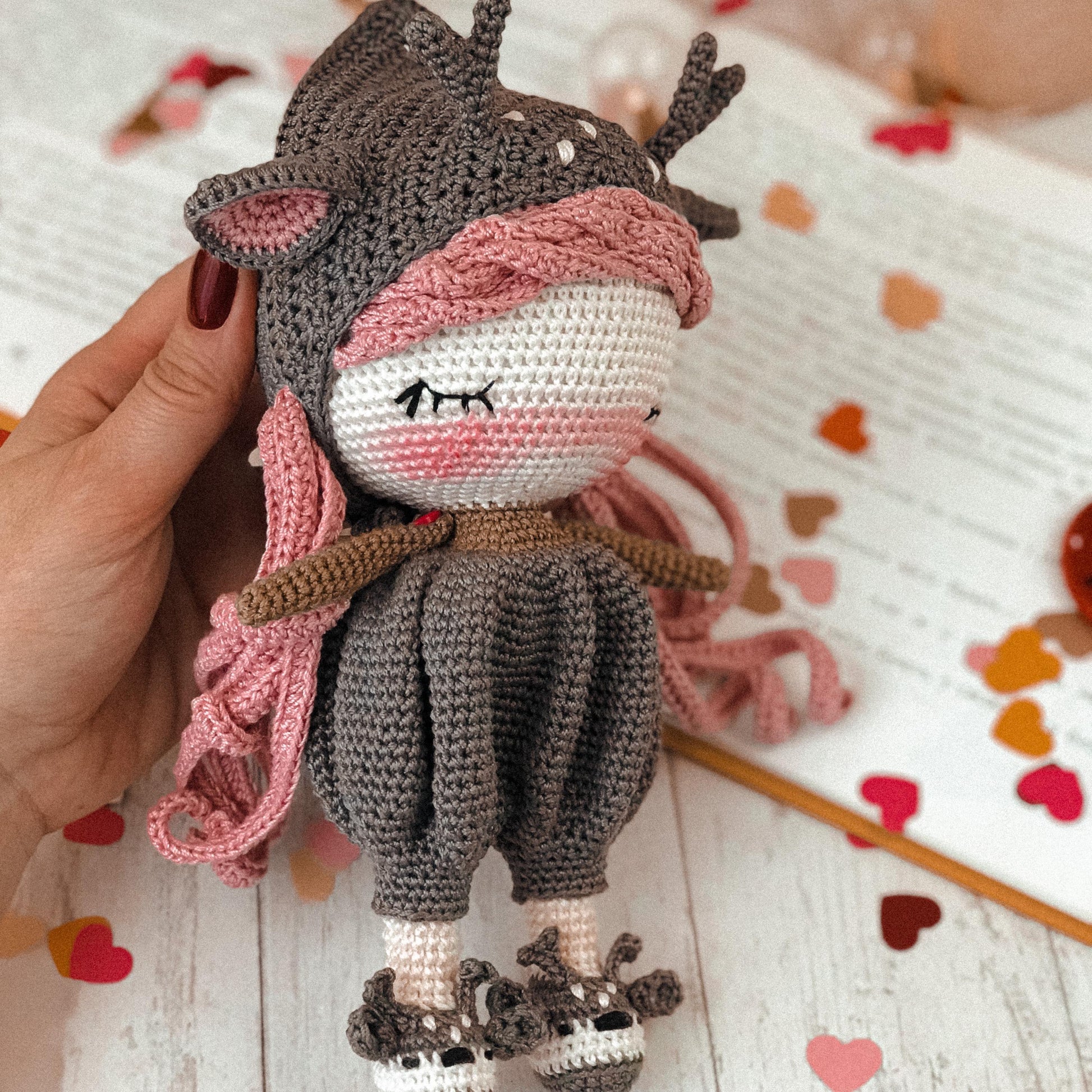 a hand holding a small stuffed animal on top of a table