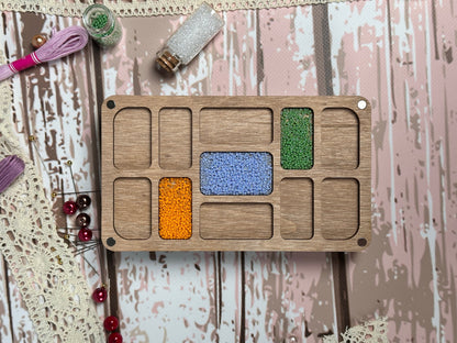 a wooden tray with different colored beads on it