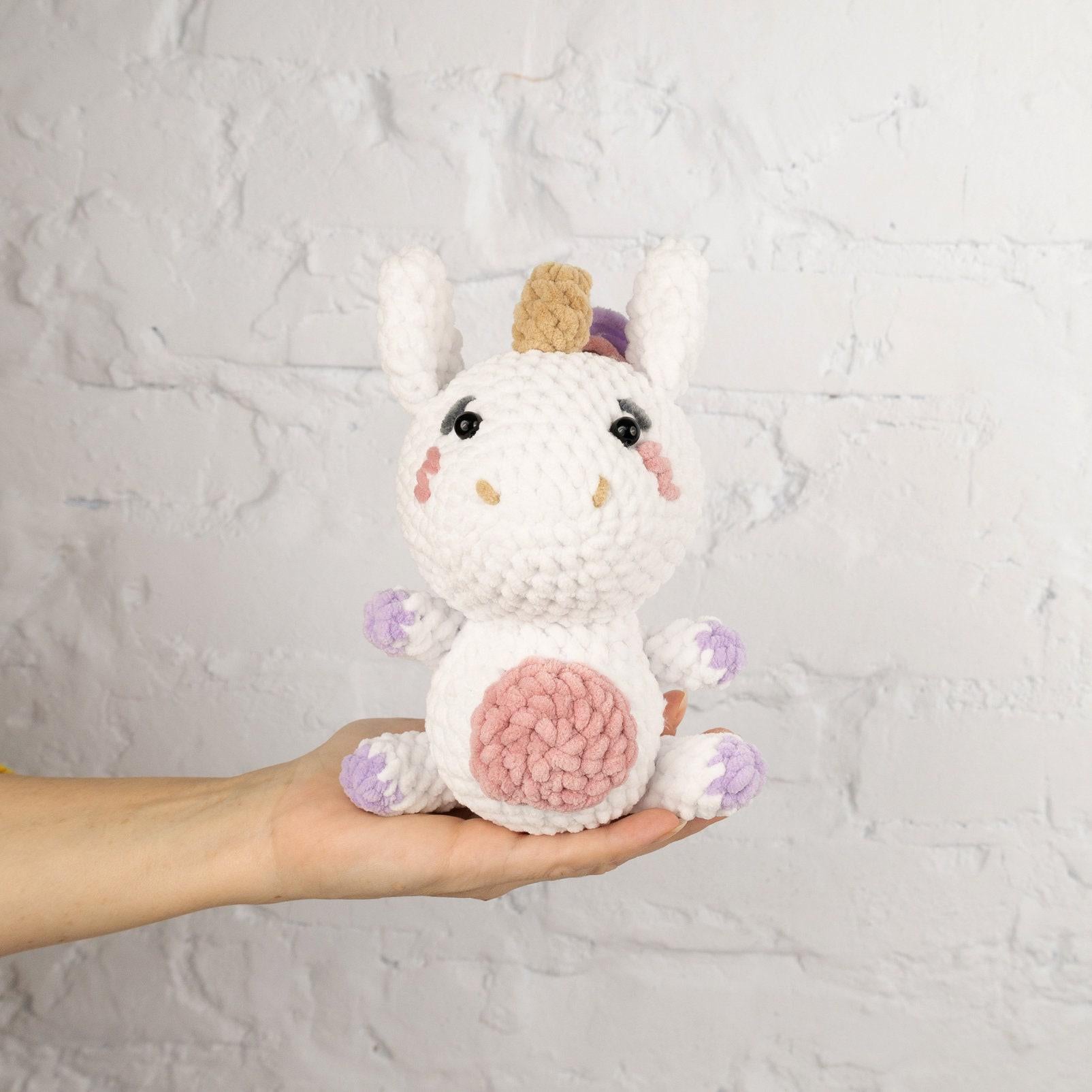 a hand holding a small crocheted stuffed animal