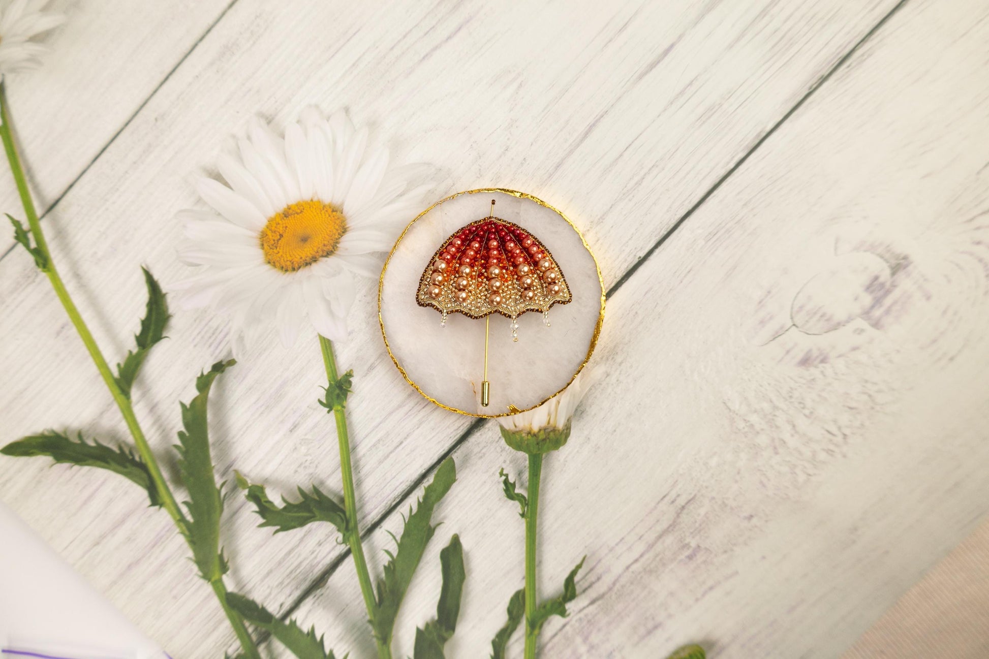 a red and gold brooch sitting on top of a white table