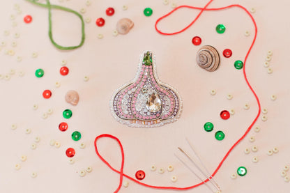 a close-up view of a decorative piece, possibly a brooch or pendant, surrounded by various craft supplies such as beads, strings, and buttons.