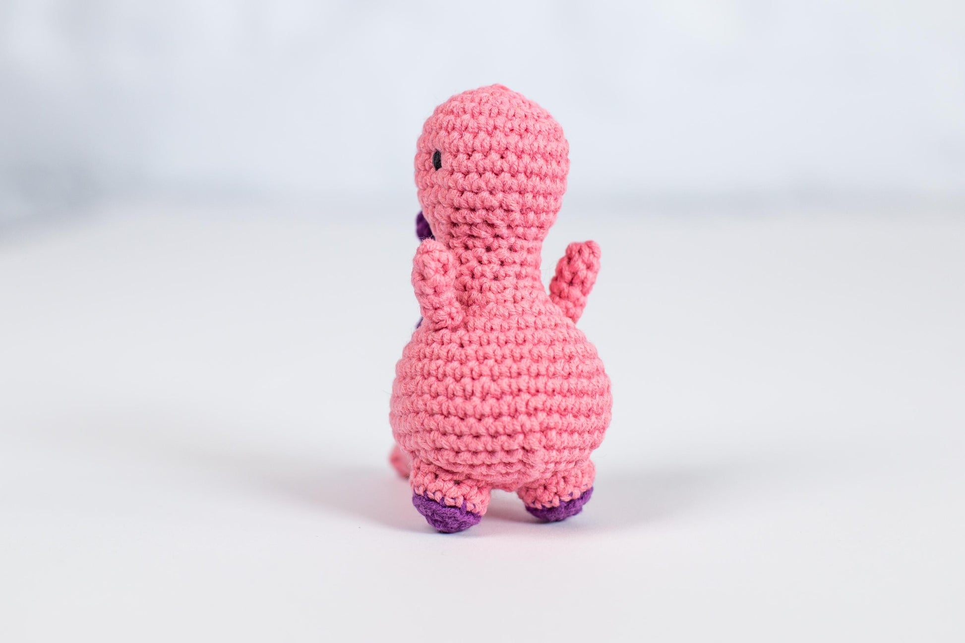 a pink crocheted toy sitting on top of a white table