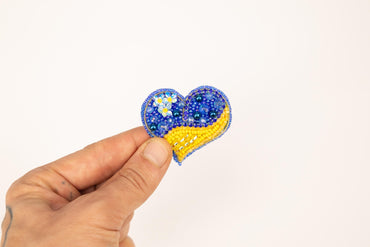 a hand holding a beaded heart shaped object