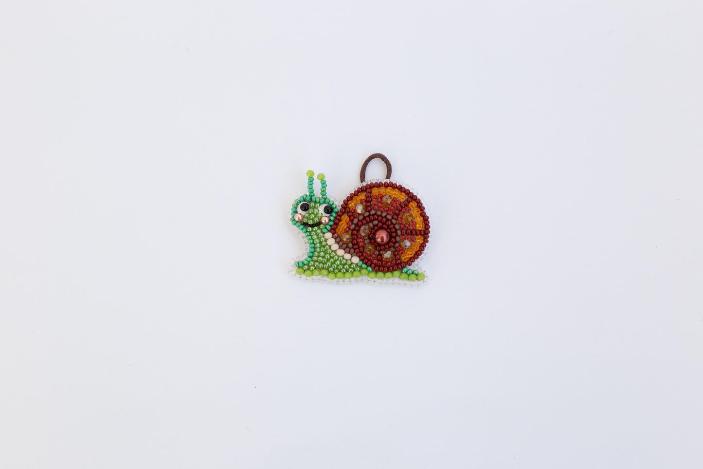 A colorful, beaded snail ornament is displayed against a plain white background.