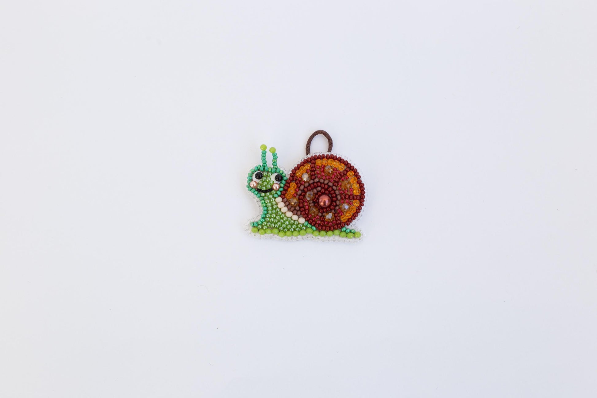 A colorful, beaded snail ornament is displayed against a plain white background.