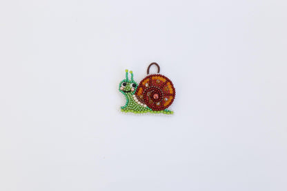 A colorful, beaded snail ornament is displayed against a plain white background.