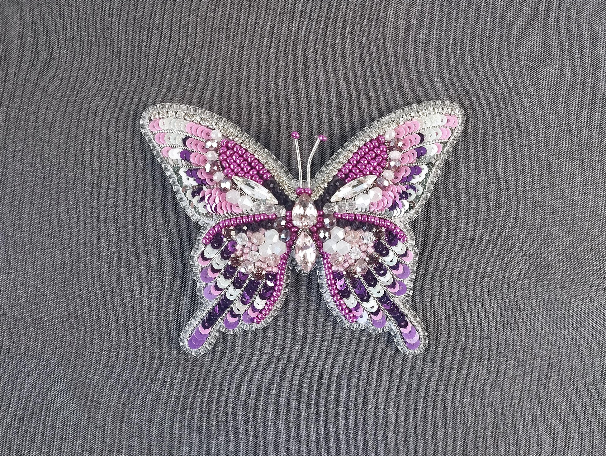 a pink and purple butterfly brooch sitting on top of a table