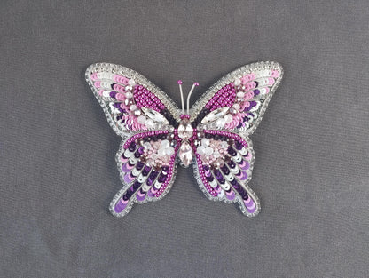 a pink and purple butterfly brooch sitting on top of a table