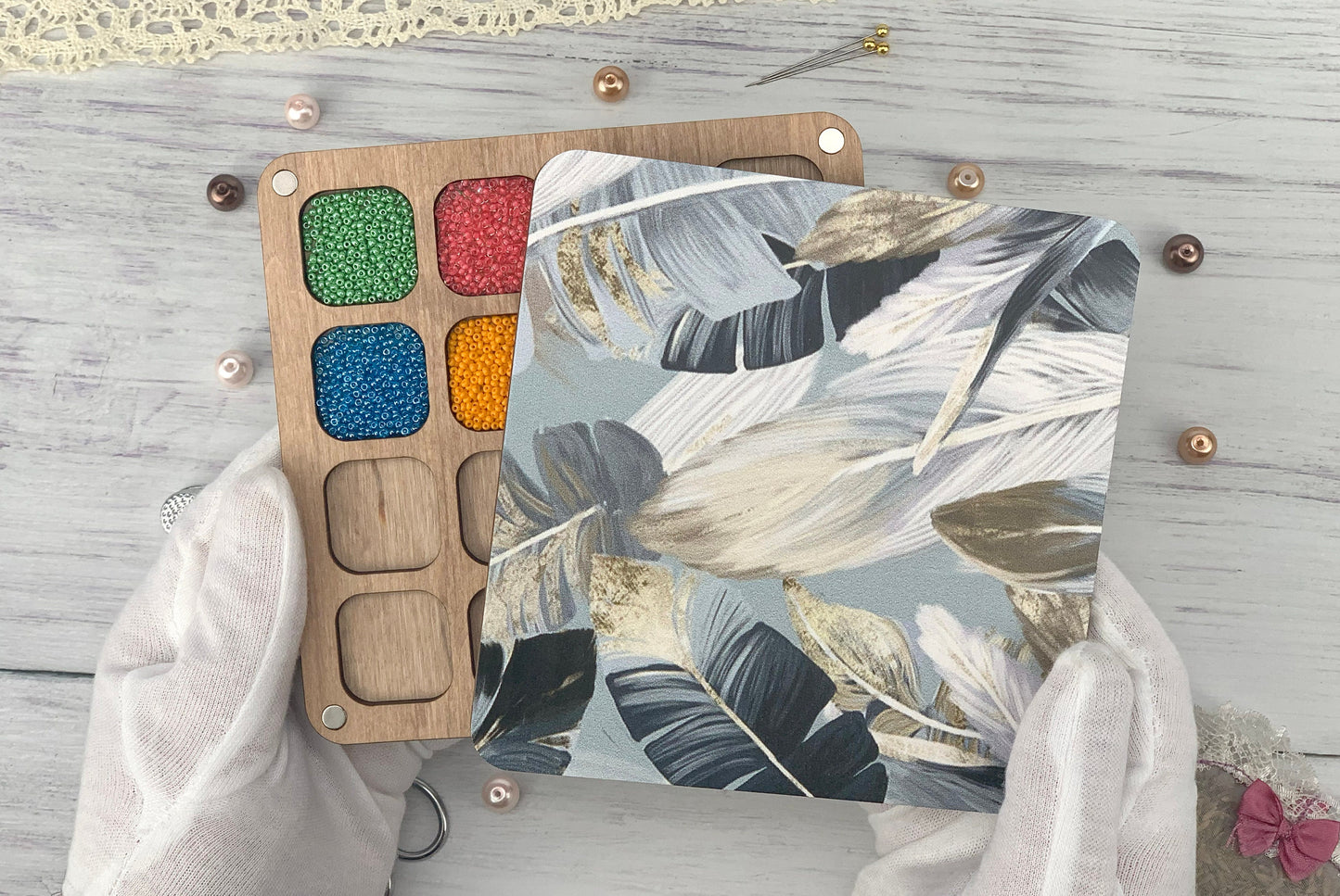 a person&#39;s hands holding a palette of paint next to a wooden board with