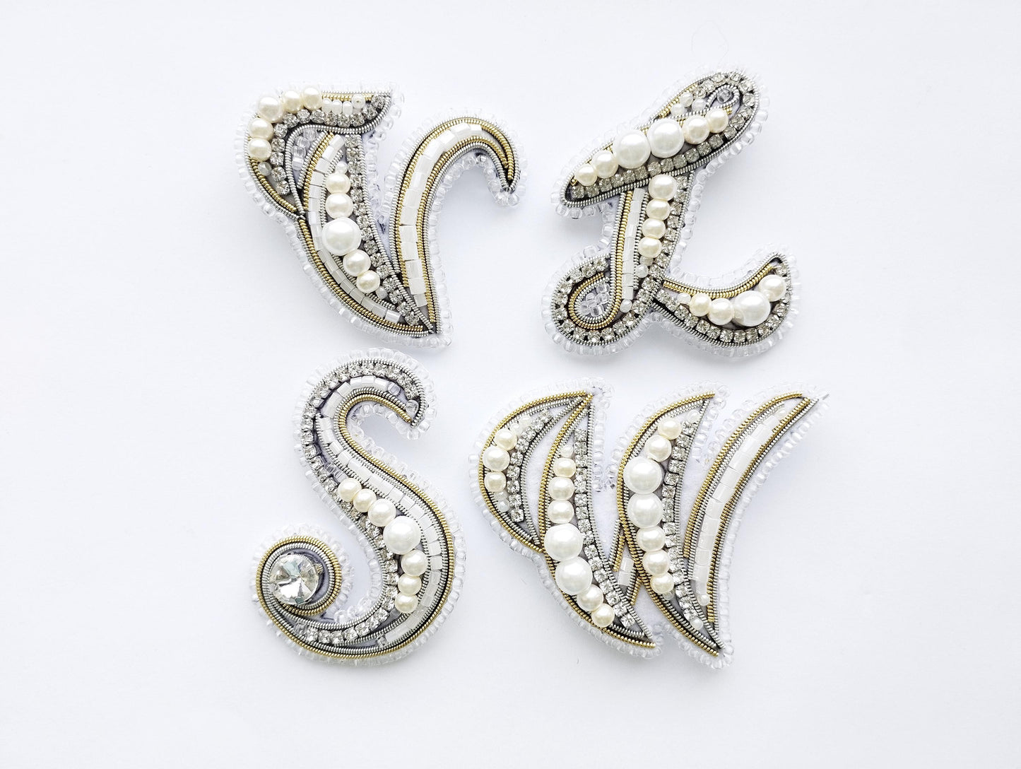 four decorative pieces made of pearls and rhinestones, arranged in a square formation on a white background.