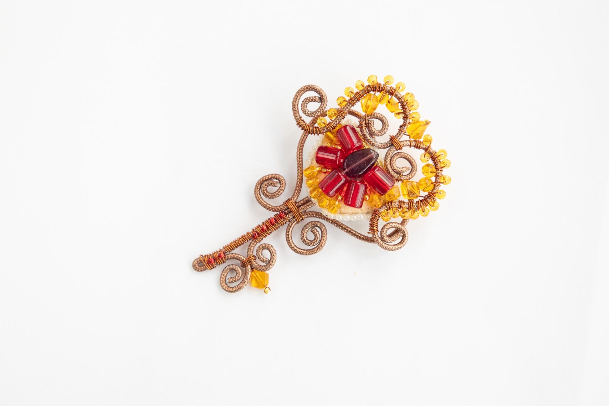 a brooch with a red and yellow flower on it