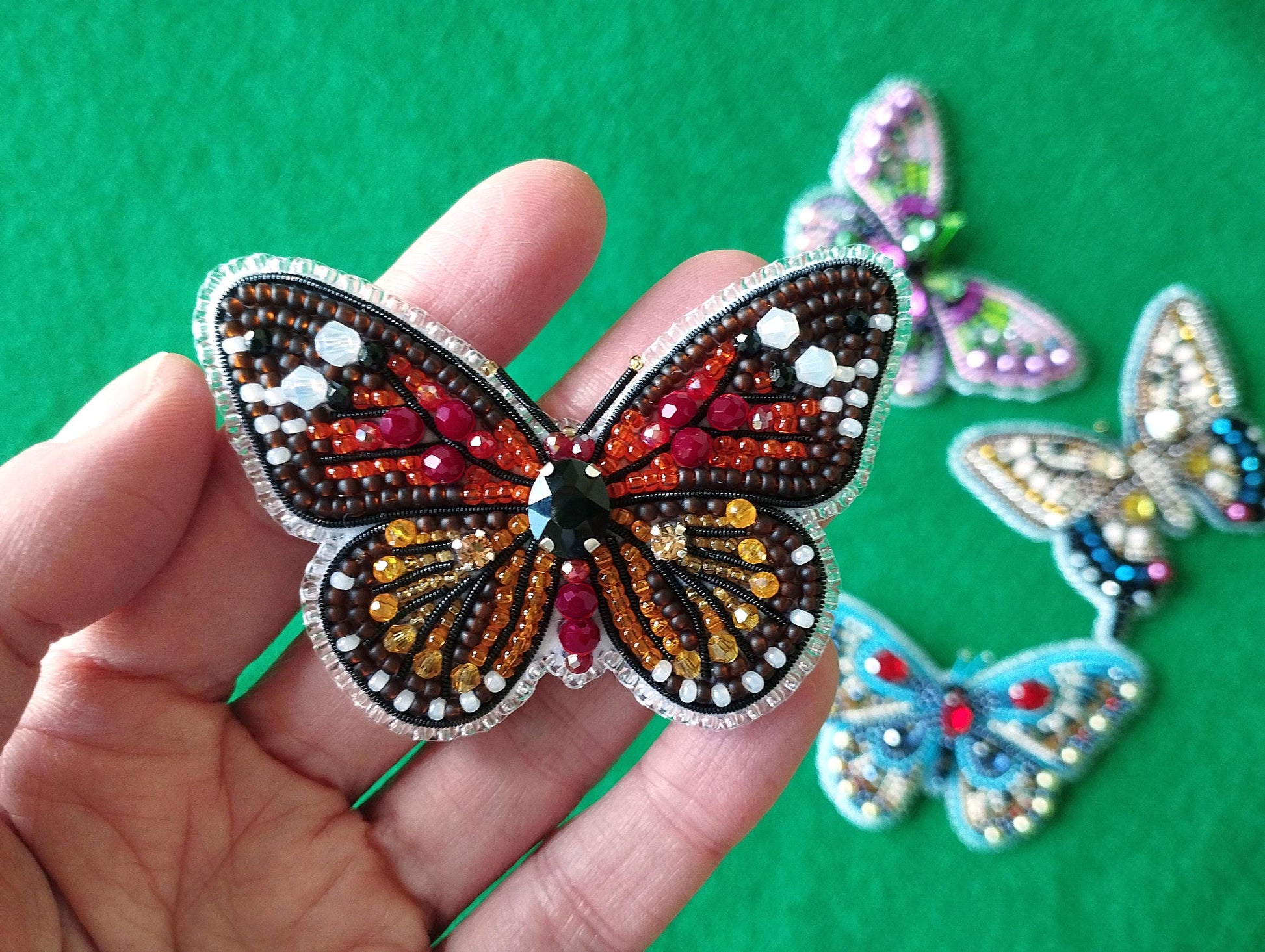 a hand is holding a small butterfly brooch