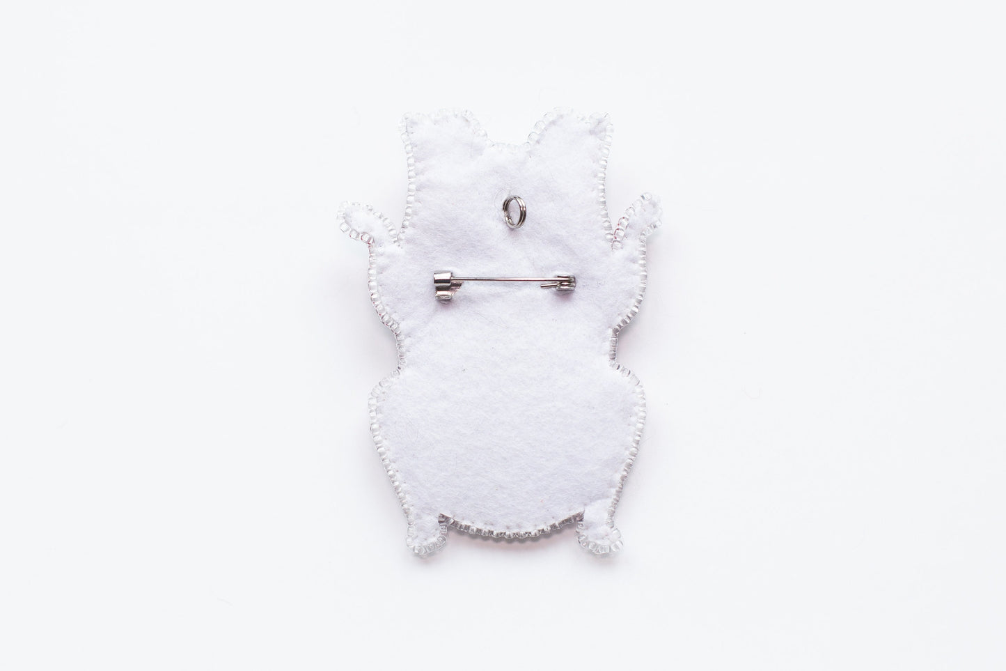 a white brooch with a silver pin on it