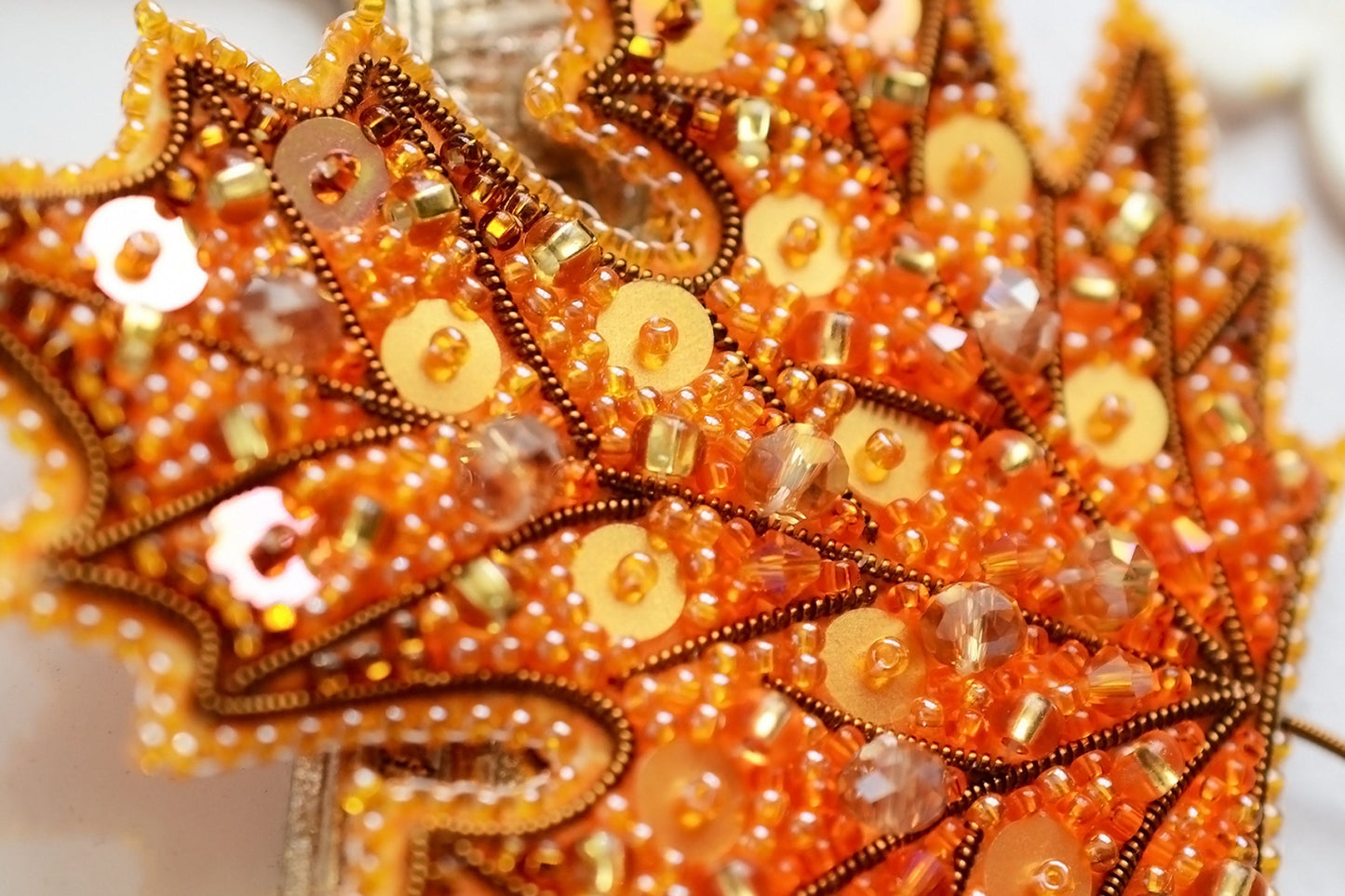 a close up of an orange beaded leaf