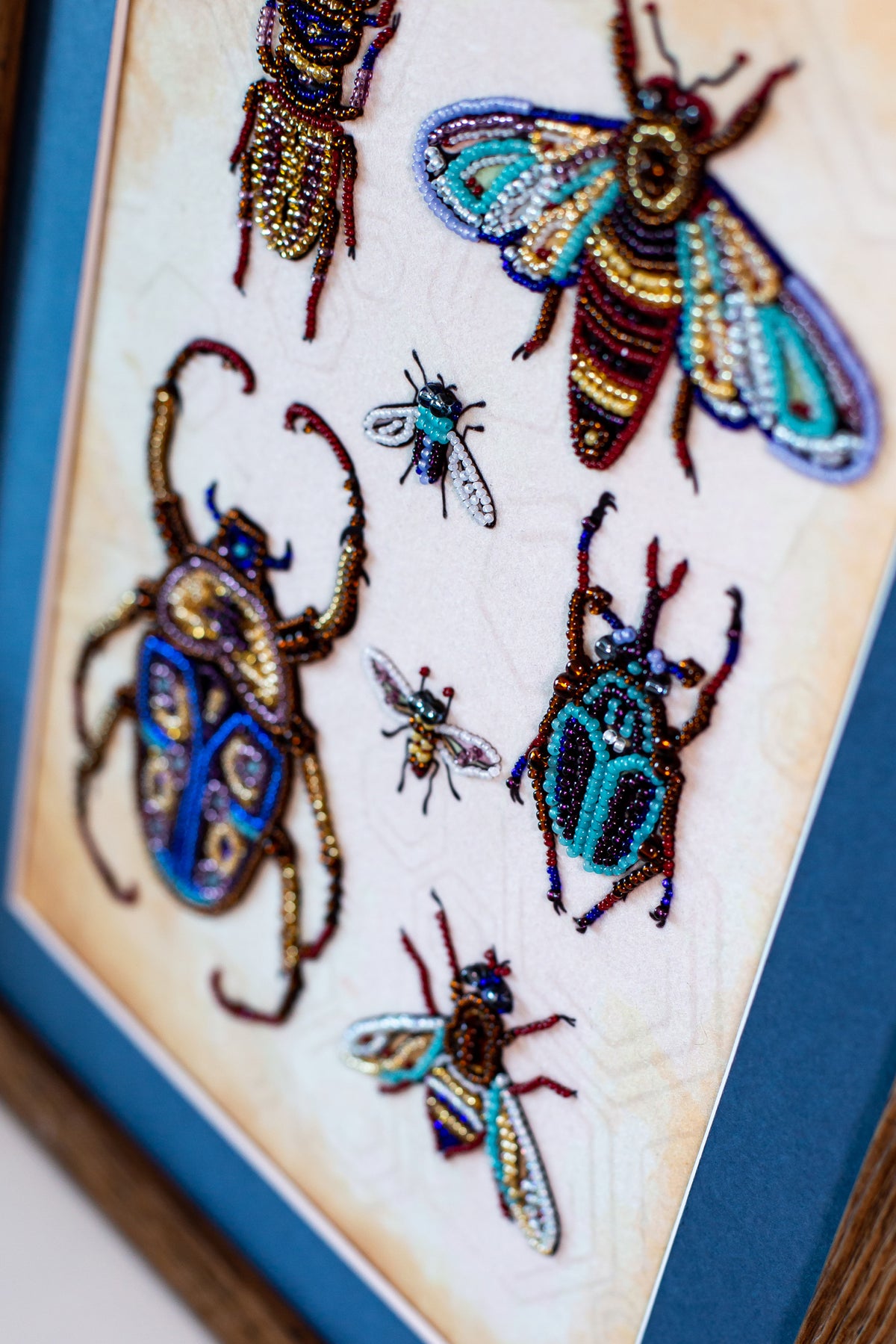 a close-up view of a framed collage of various colorful and intricately designed insects, including a large dragonfly, a smaller bee, and several other insects with unique patterns and colors.