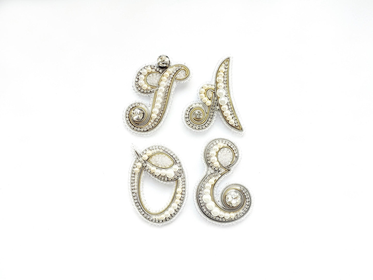four ornate pieces of jewelry, including brooches and pendants, arranged in a square formation against a white background.