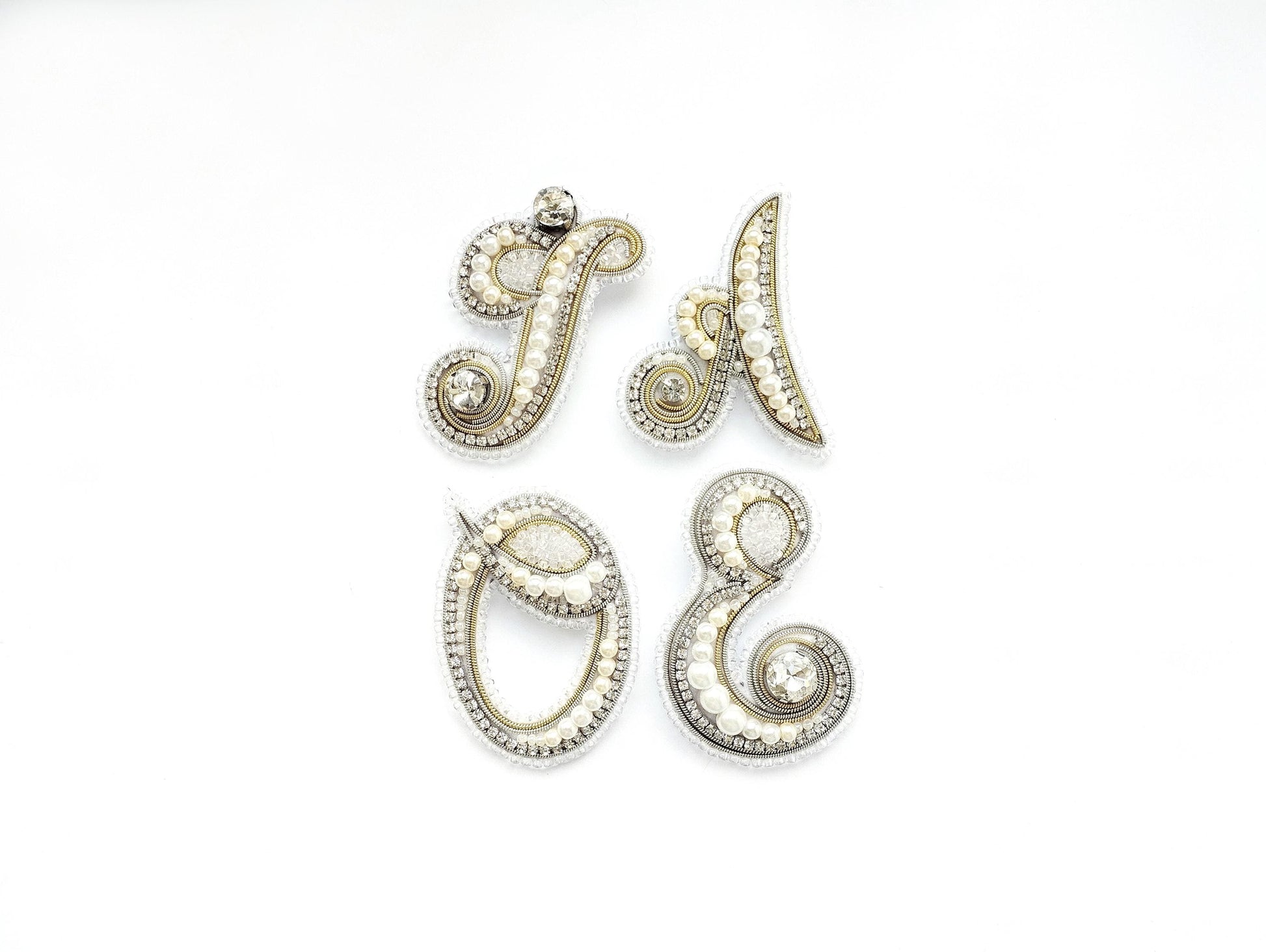 four ornate pieces of jewelry, including brooches and pendants, arranged in a square formation against a white background.