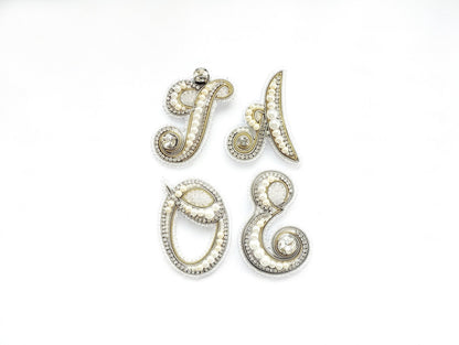 four ornate pieces of jewelry, including brooches and pendants, arranged in a square formation against a white background.
