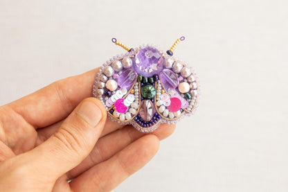 a person holding a beaded brooch in their hand