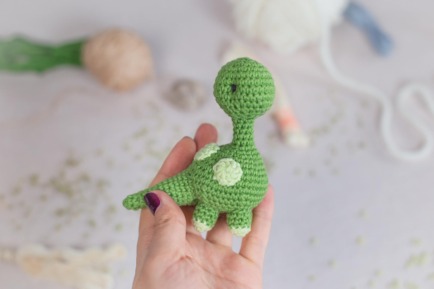 a hand holding a small green crocheted toy