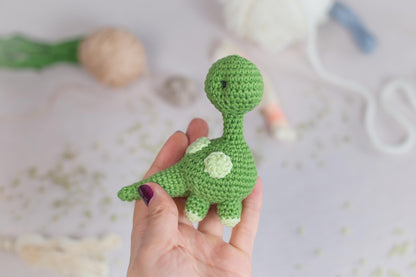 a hand holding a small green crocheted toy