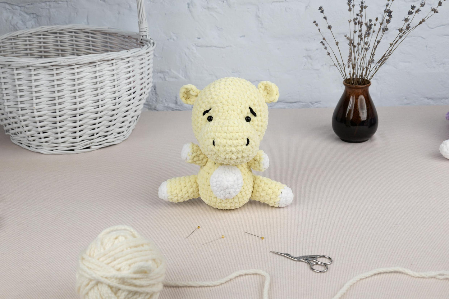 a crocheted teddy bear sitting on a table next to a ball of yarn