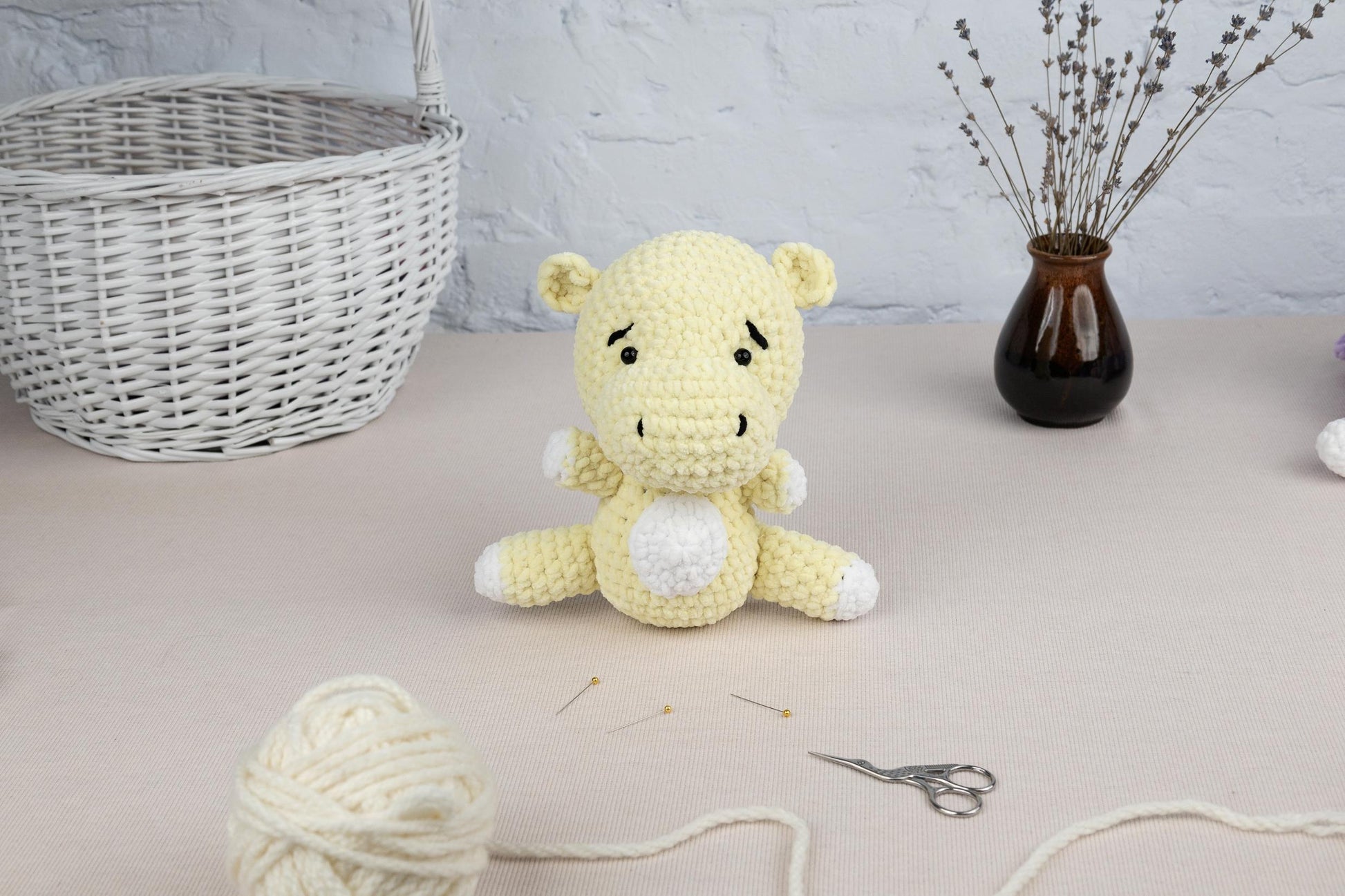 a crocheted teddy bear sitting on a table next to a ball of yarn