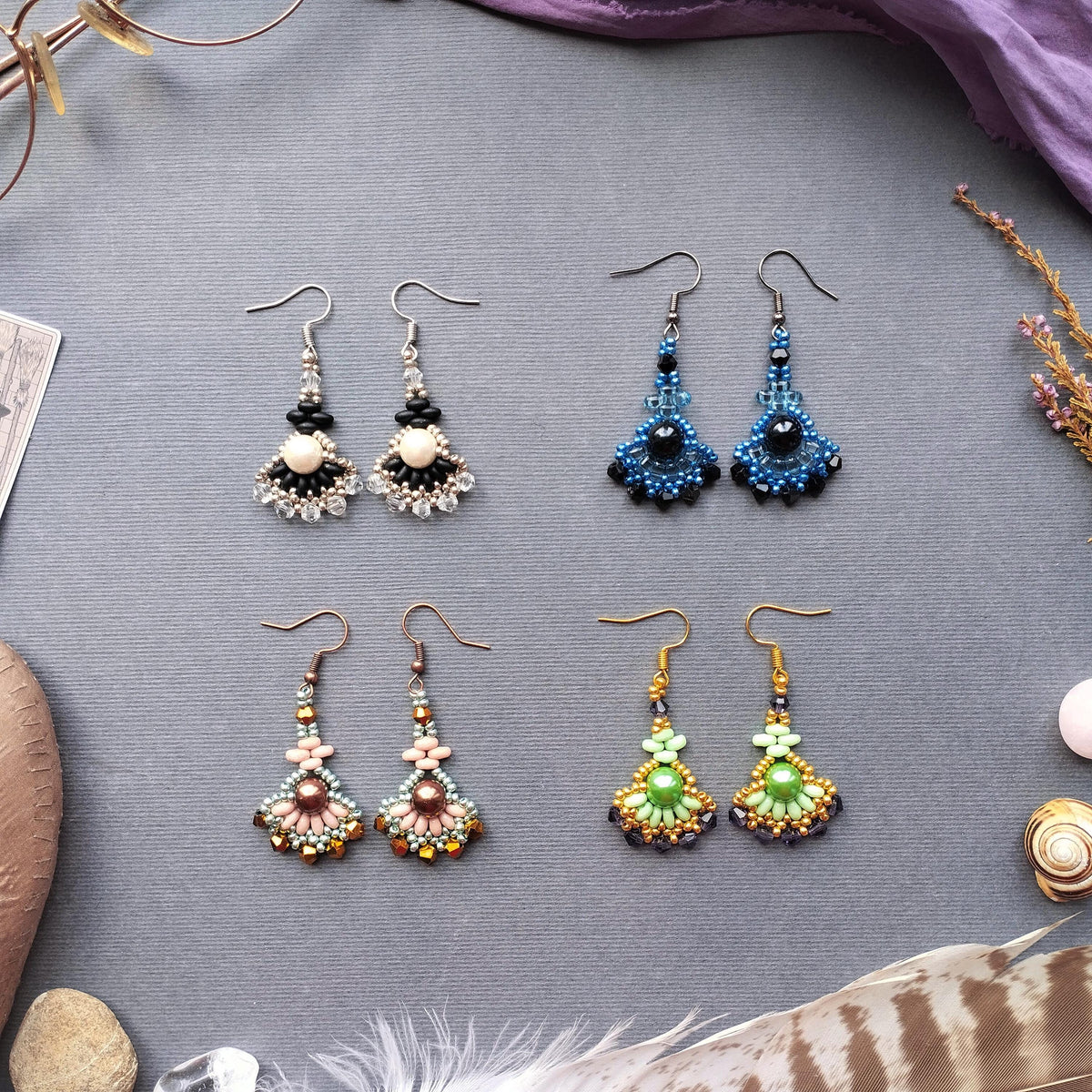 a collection of four pairs of earrings, each with unique designs and colors, arranged on a gray background.