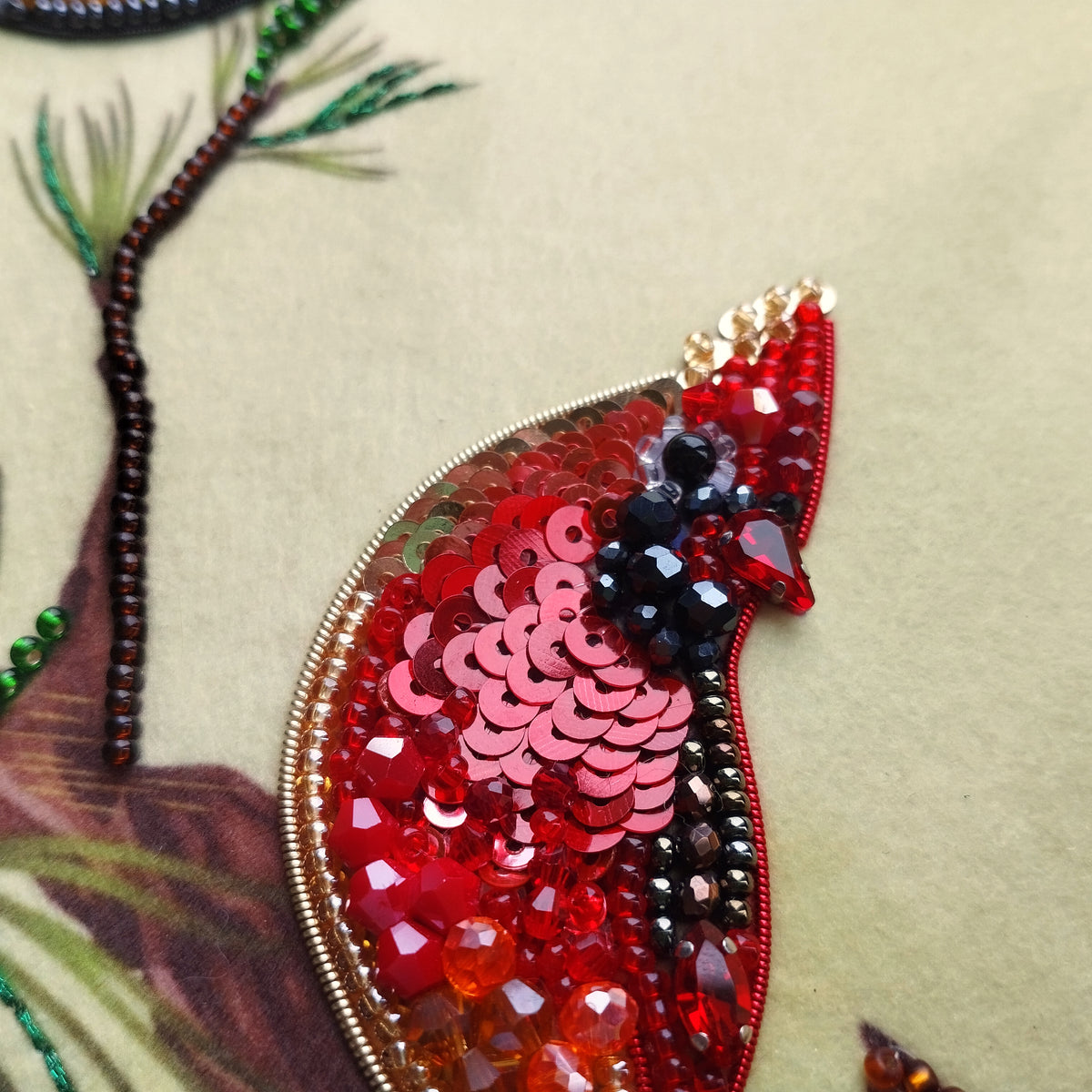 a close-up view of a vibrant red sequin patch with a bird-like design, set against a neutral background.