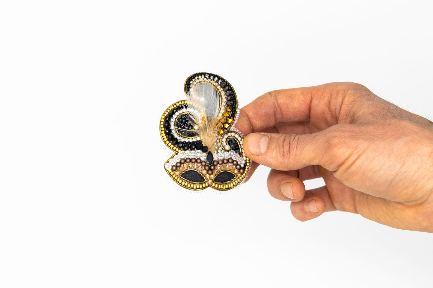 a hand holding a brooch with a design on it