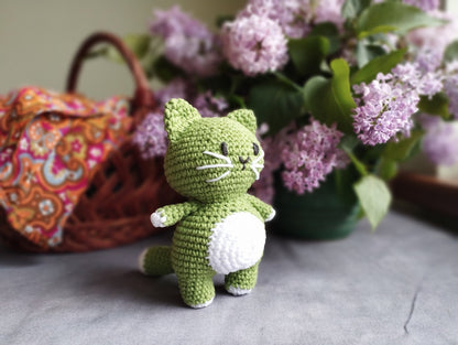 a crocheted cat and two birds are next to a vase with flowers