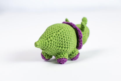 a crocheted green turtle with a purple hat