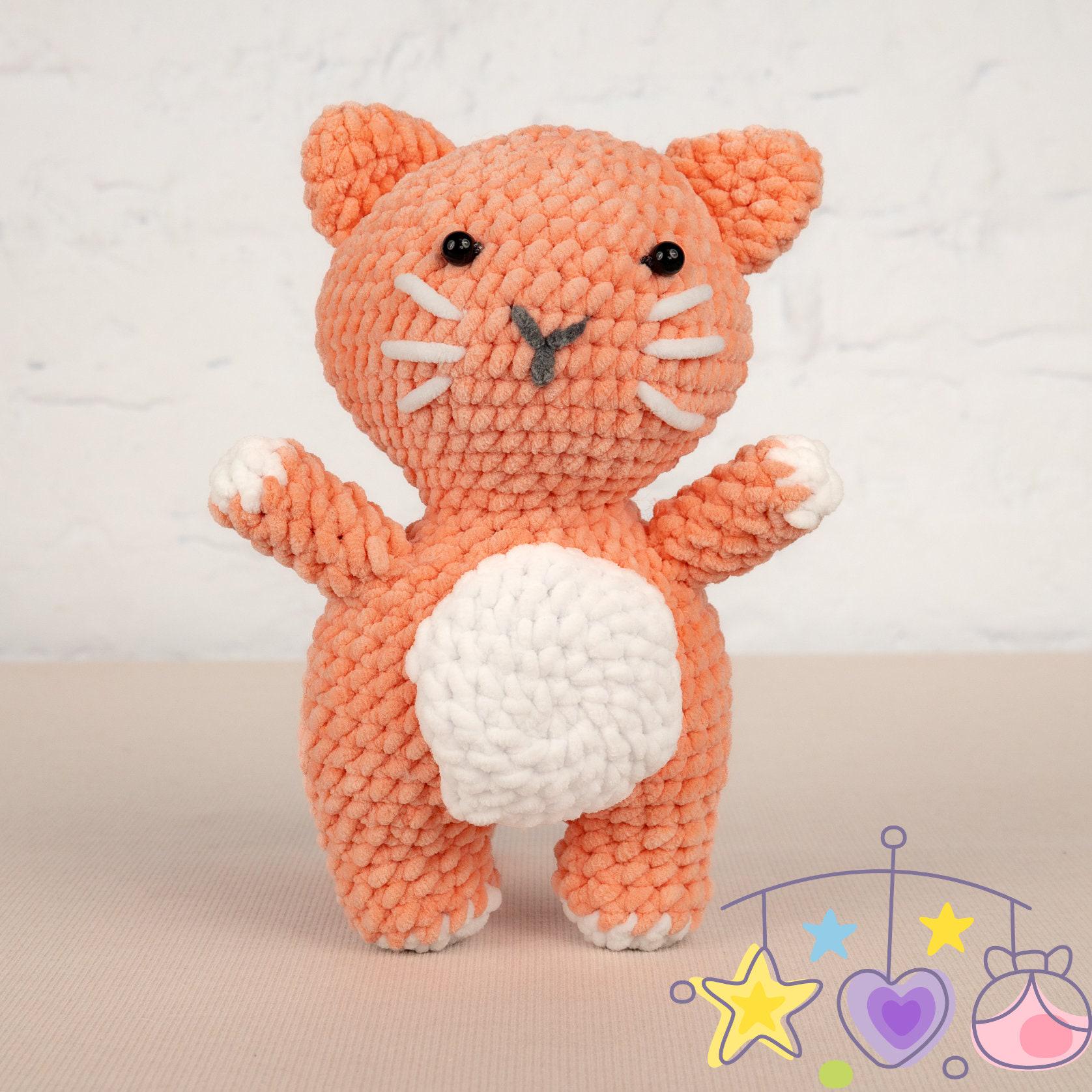 a crocheted cat next to a ball of yarn