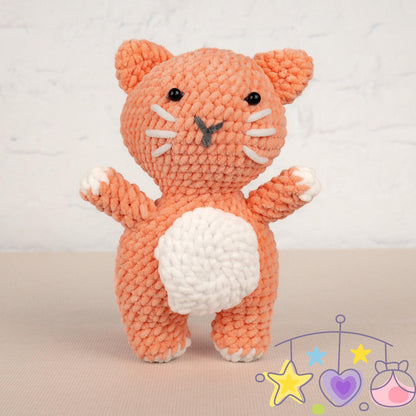 a crocheted cat next to a ball of yarn